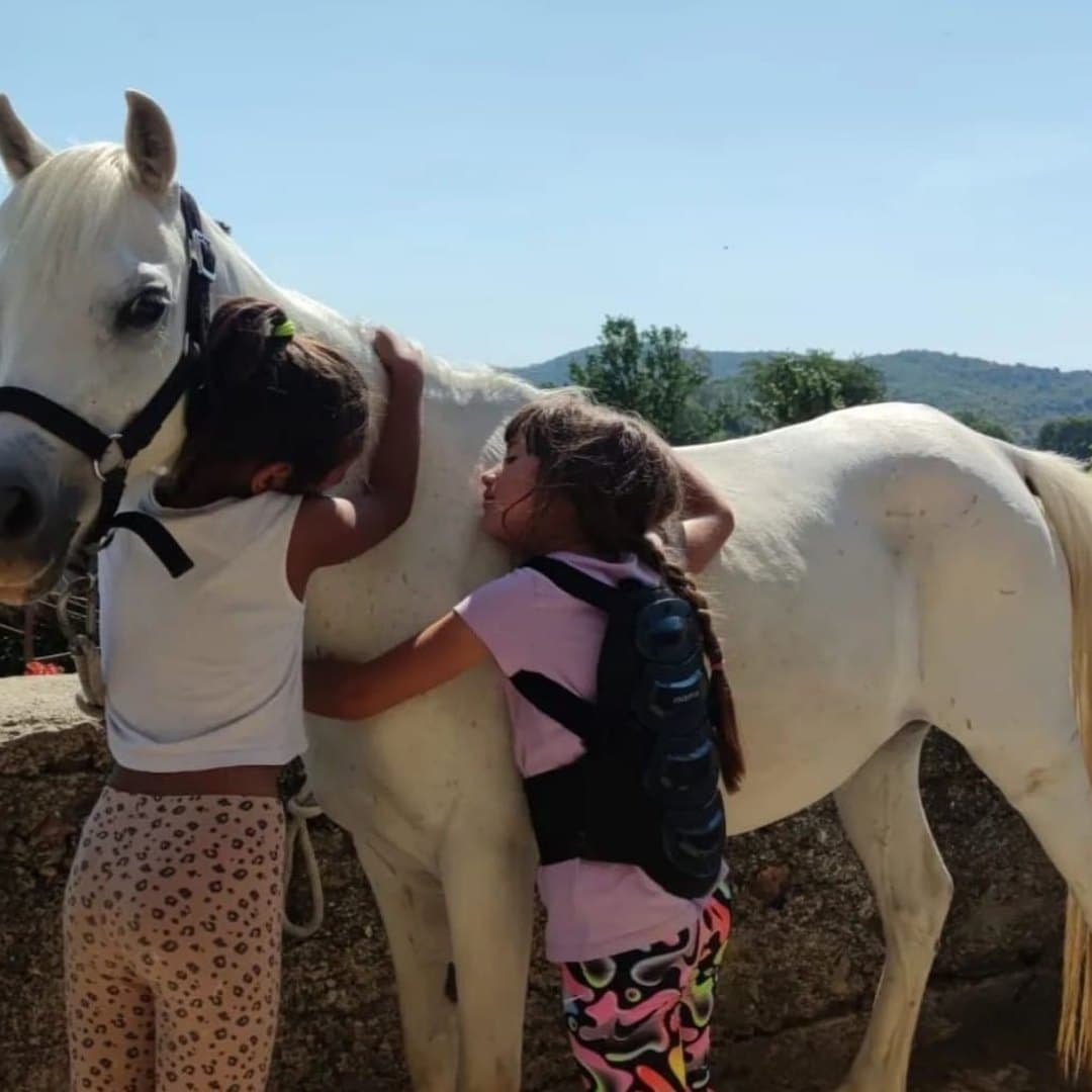 Dos niñas de la comunidad abrazando a uno de los caballos rescatados